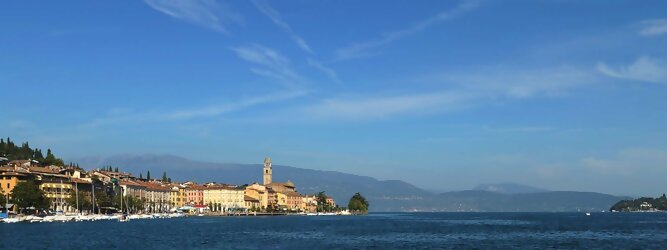 Trip Anti Aging beliebte Urlaubsziele am Gardasee -  Mit einer Fläche von 370 km² ist der Gardasee der größte See Italiens. Es liegt am Fuße der Alpen und erstreckt sich über drei Staaten: Lombardei, Venetien und Trentino. Die maximale Tiefe des Sees beträgt 346 m, er hat eine längliche Form und sein nördliches Ende ist sehr schmal. Dort ist der See von den Bergen der Gruppo di Baldo umgeben. Du trittst aus deinem gemütlichen Hotelzimmer und es begrüßt dich die warme italienische Sonne. Du blickst auf den atemberaubenden Gardasee, der in zahlreichen Blautönen schimmert - von tiefem Dunkelblau bis zu funkelndem Türkis. Majestätische Berge umgeben dich, während die Brise sanft deine Haut streichelt und der Duft von blühenden Zitronenbäumen deine Nase kitzelt. Du schlenderst die malerischen, engen Gassen entlang, vorbei an farbenfrohen, blumengeschmückten Häusern. Vereinzelt unterbricht das fröhliche Lachen der Einheimischen die friedvolle Stille. Du fühlst dich wie in einem Traum, der nicht enden will. Jeder Schritt führt dich zu neuen Entdeckungen und Abenteuern. Du probierst die köstliche italienische Küche mit ihren frischen Zutaten und verführerischen Aromen. Die Sonne geht langsam unter und taucht den Himmel in ein leuchtendes Orange-rot - ein spektakulärer Anblick.